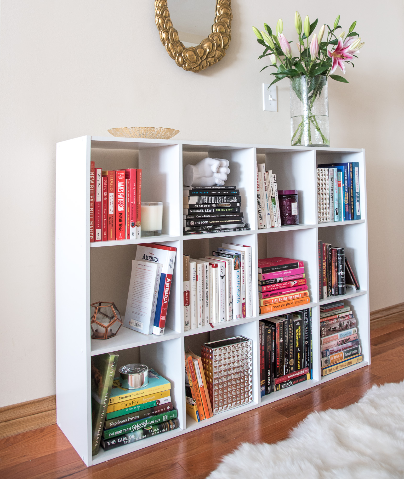 a colorful bookcase with candles and flowers