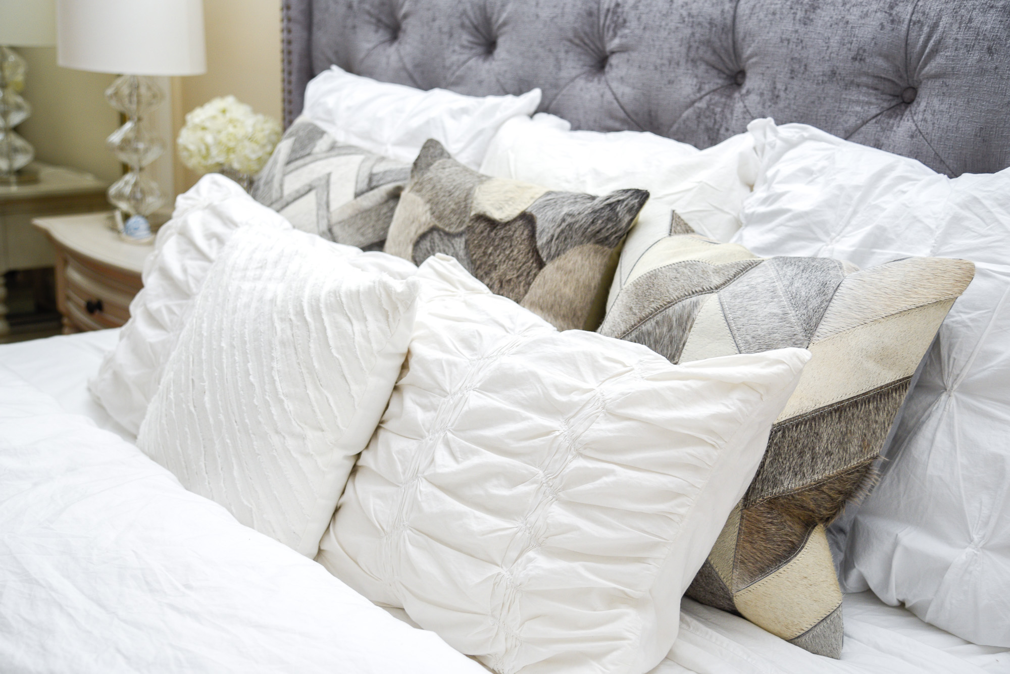 a styled bed with lots of mixed and matched pillows 