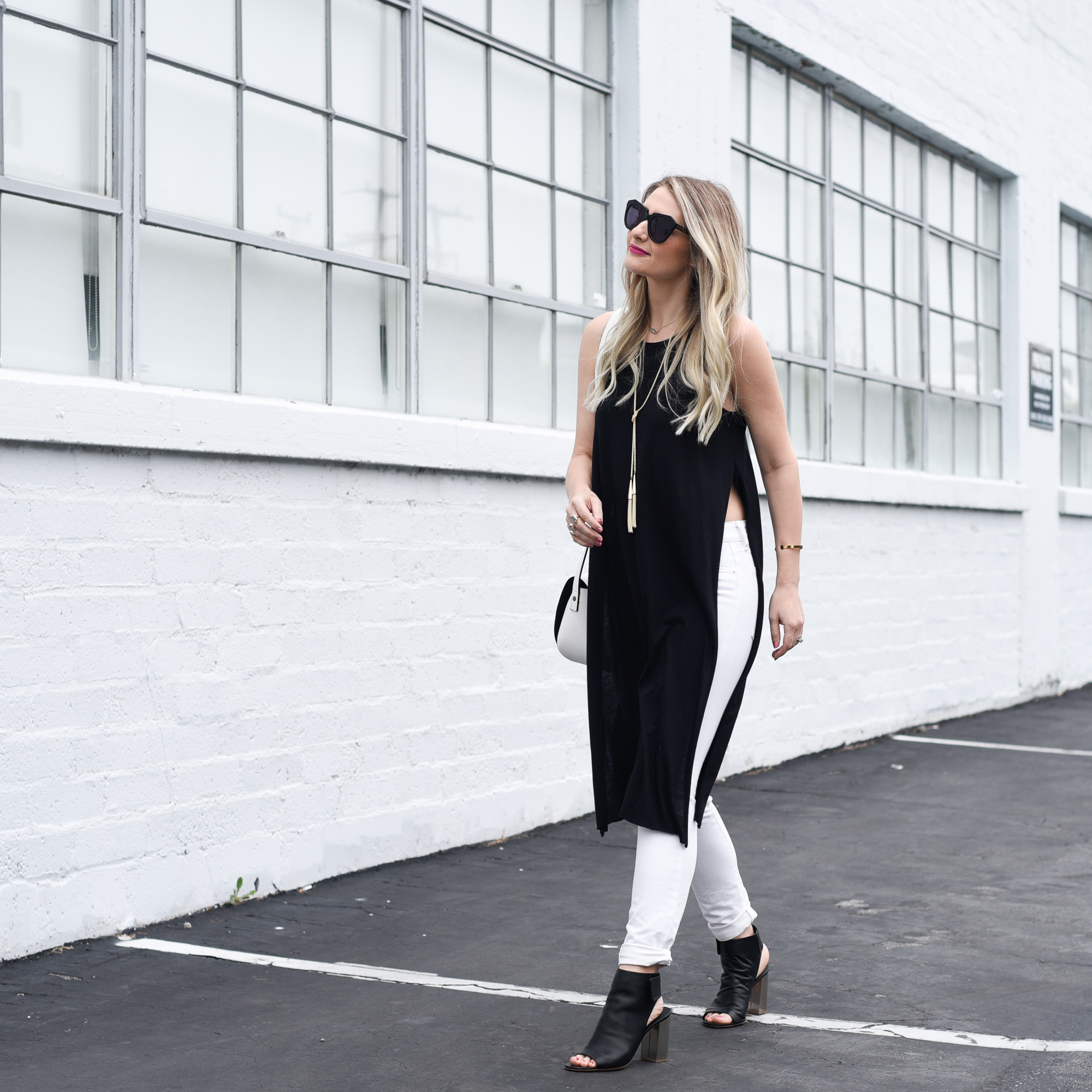 Jenna Colgrove wearing a long black tank with slits and white denim. 