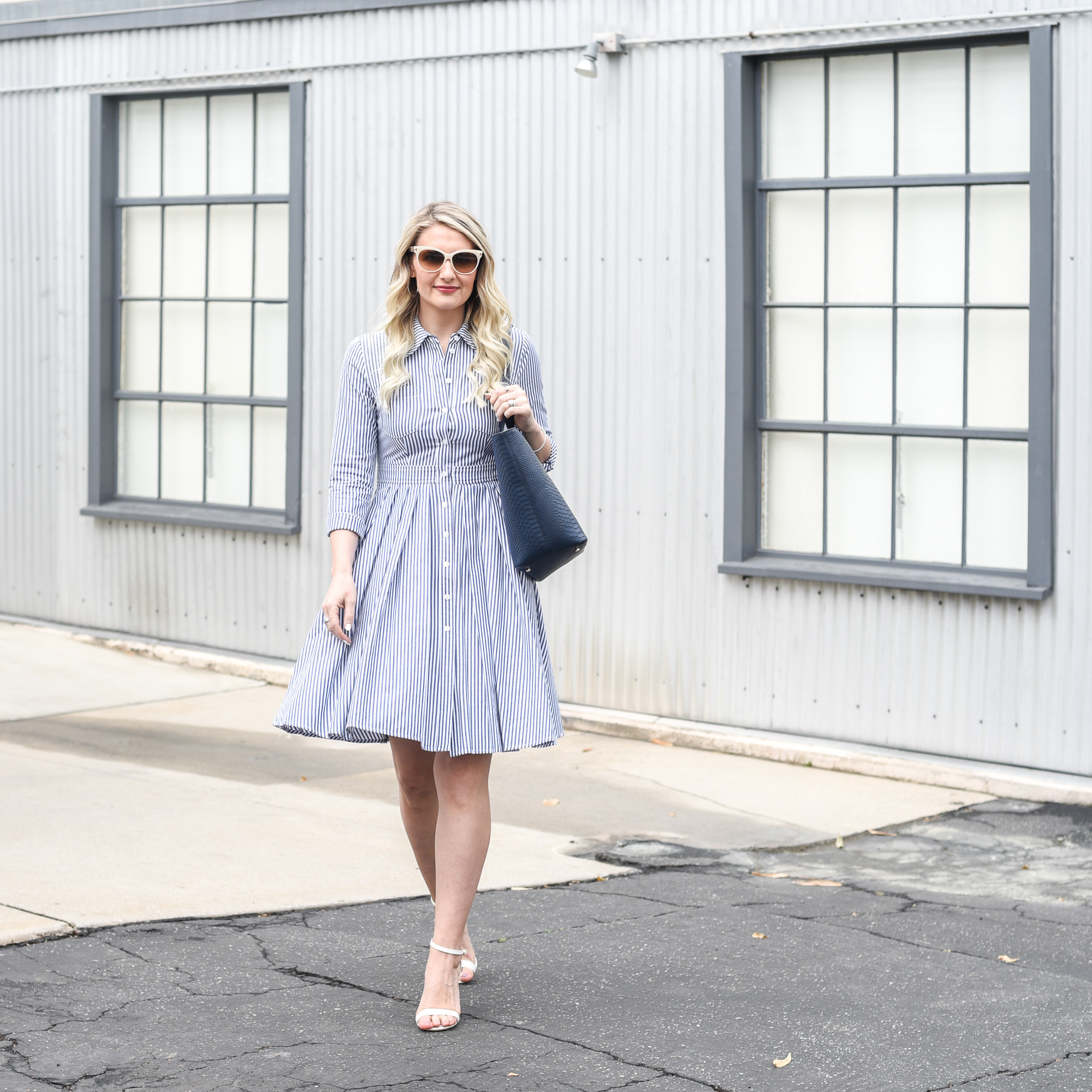 Jenna Colgrove in a striped button down dress with a navy tote.