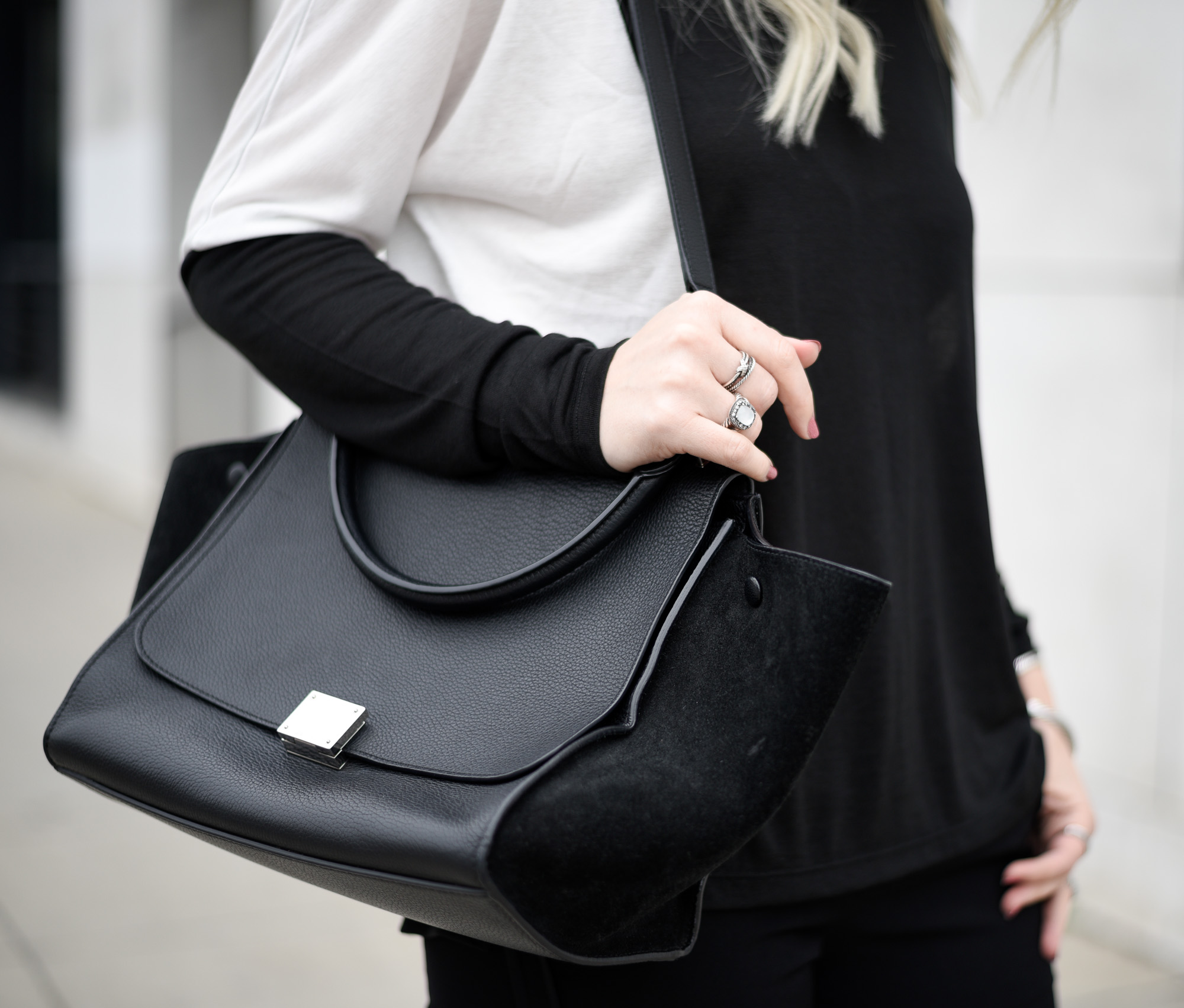 Layered silver rings with a black trapeze bag. 