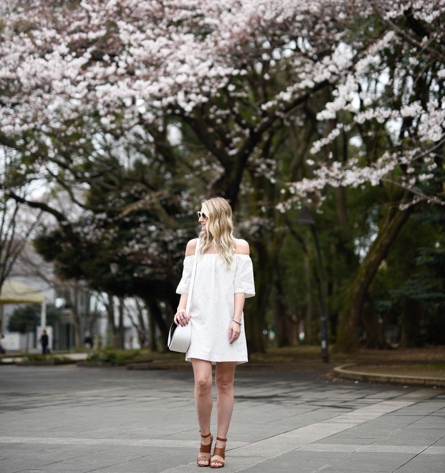 White off the shoulder dress in Ueno Park, Tokyo during cherry blossom season. 
