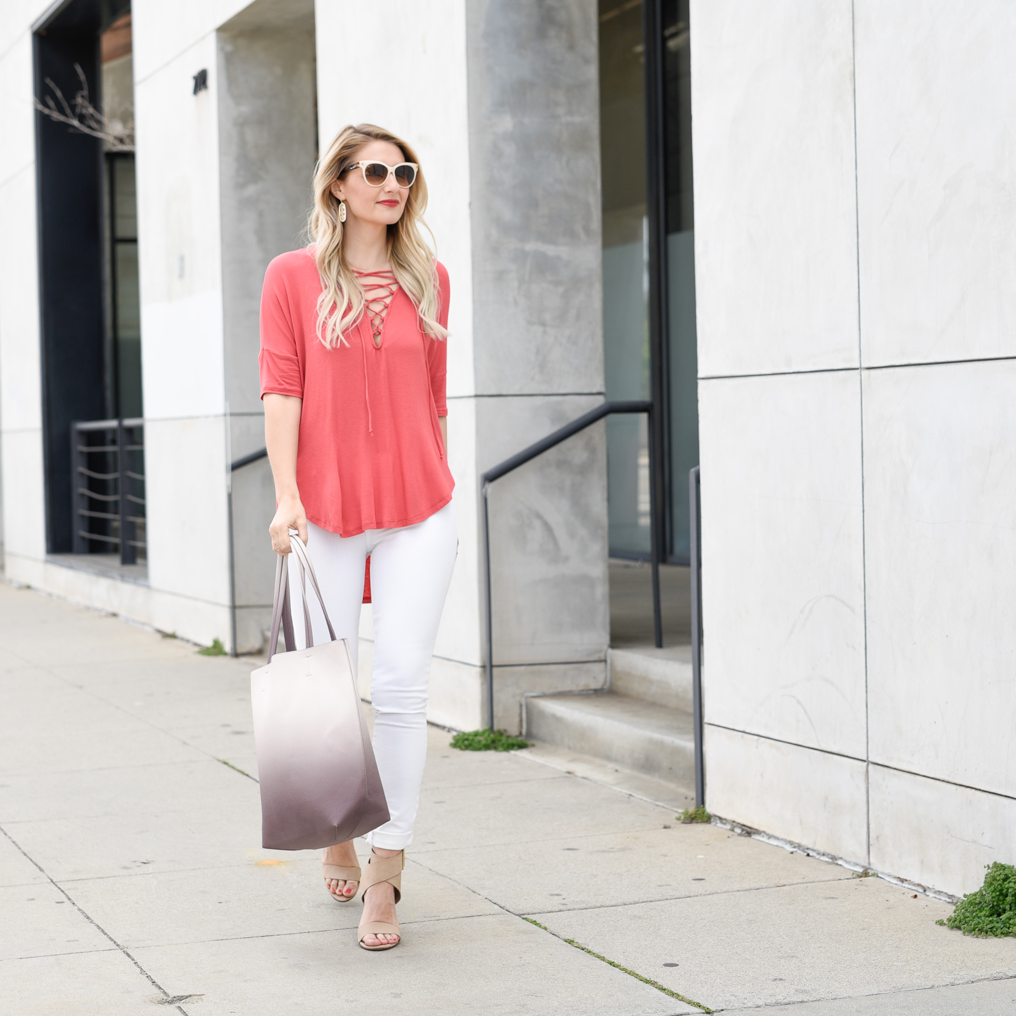 Jenna Colgrove in a coral colored lace up blouse with white skinny jeans. 