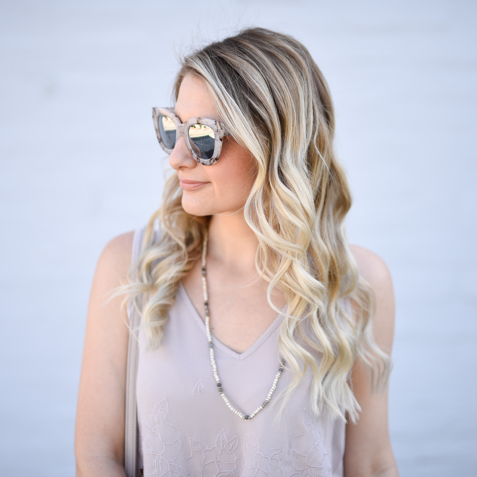 Mirrored sunglasses and a white beaded necklace. 