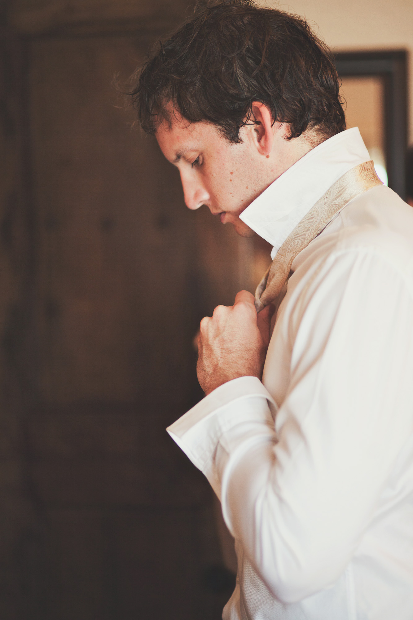 groom getting ready with a champagne and beige tie