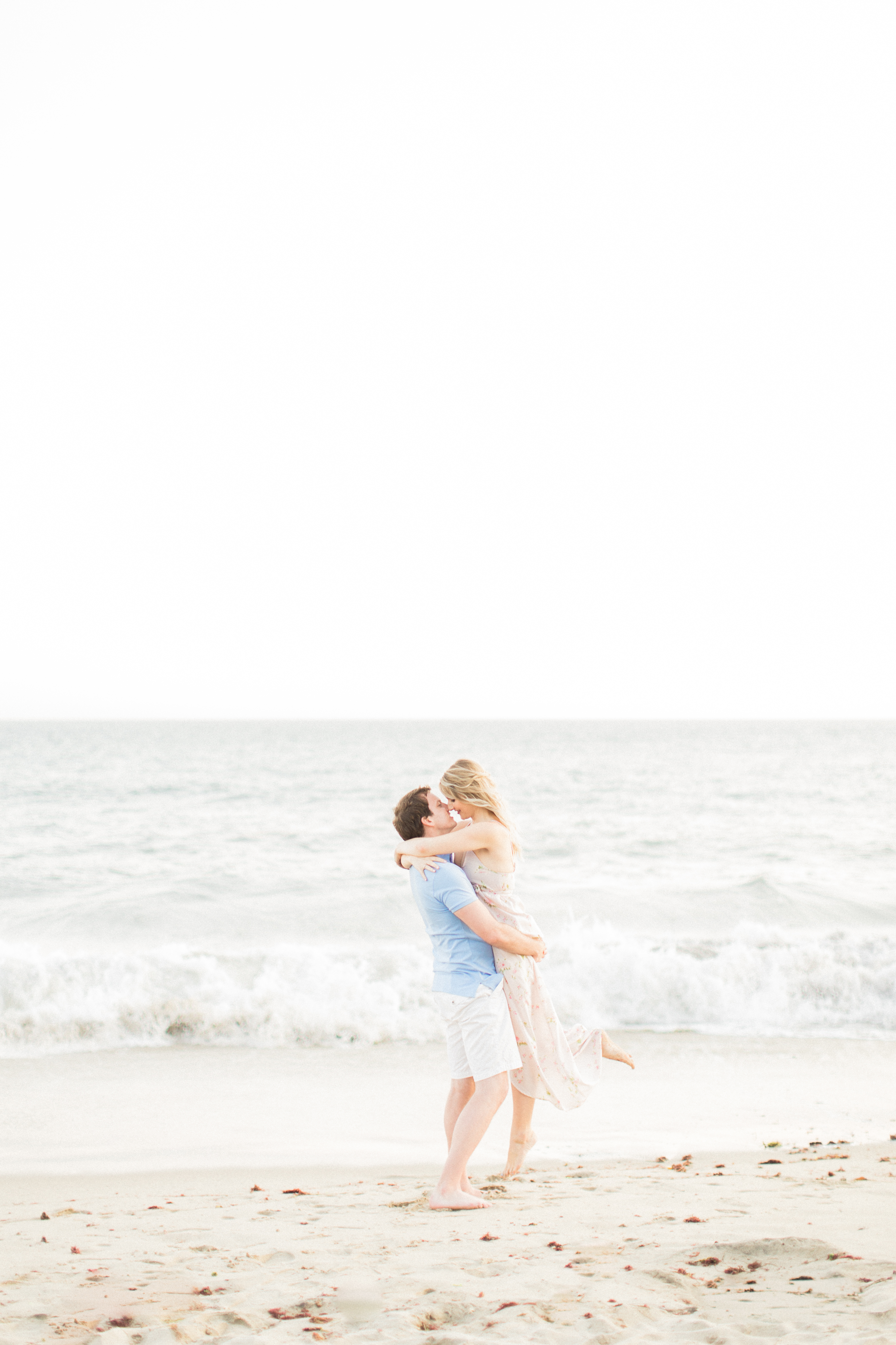 Couple hugging on the sand by the beach in California.