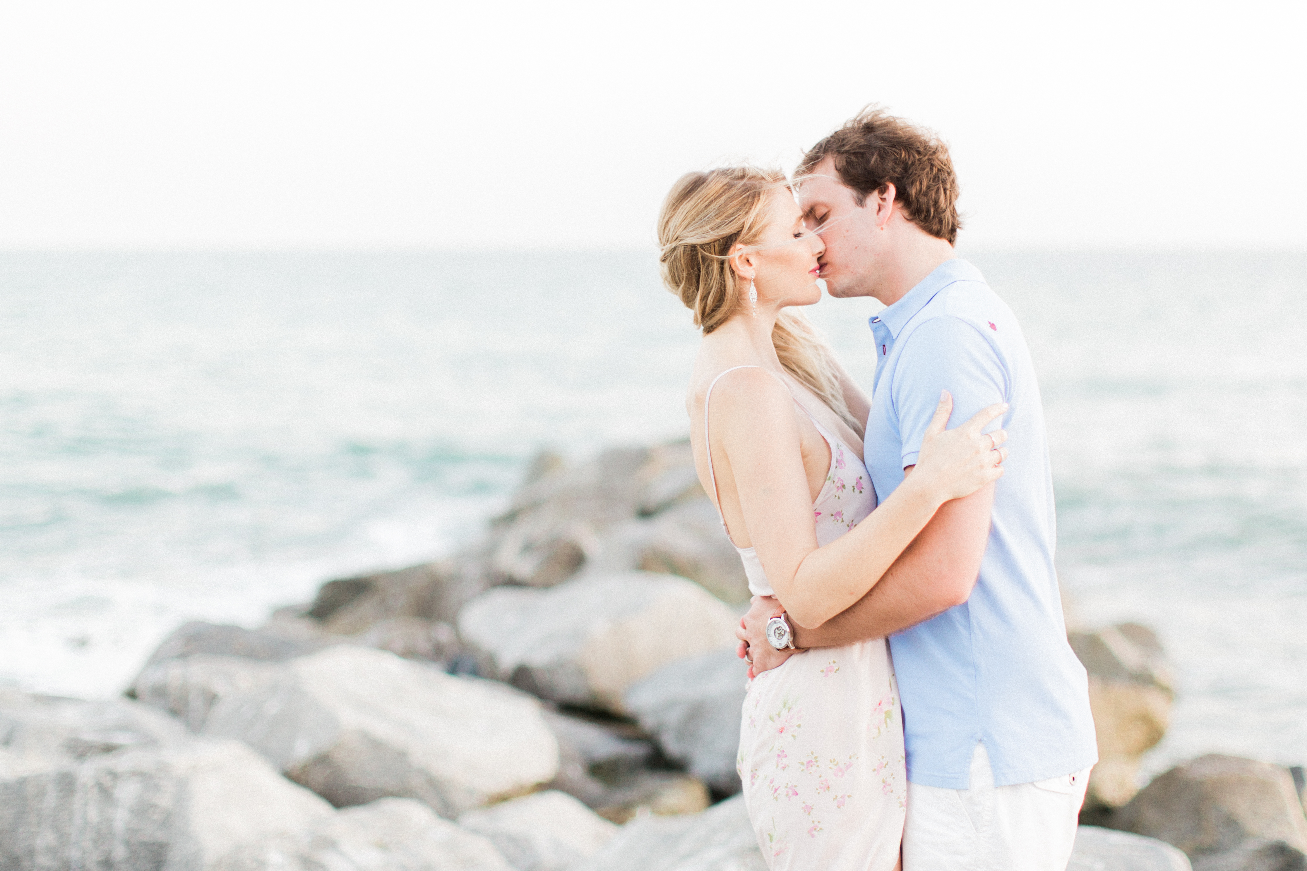 Couple kissing on the rocks by the ocean. 
