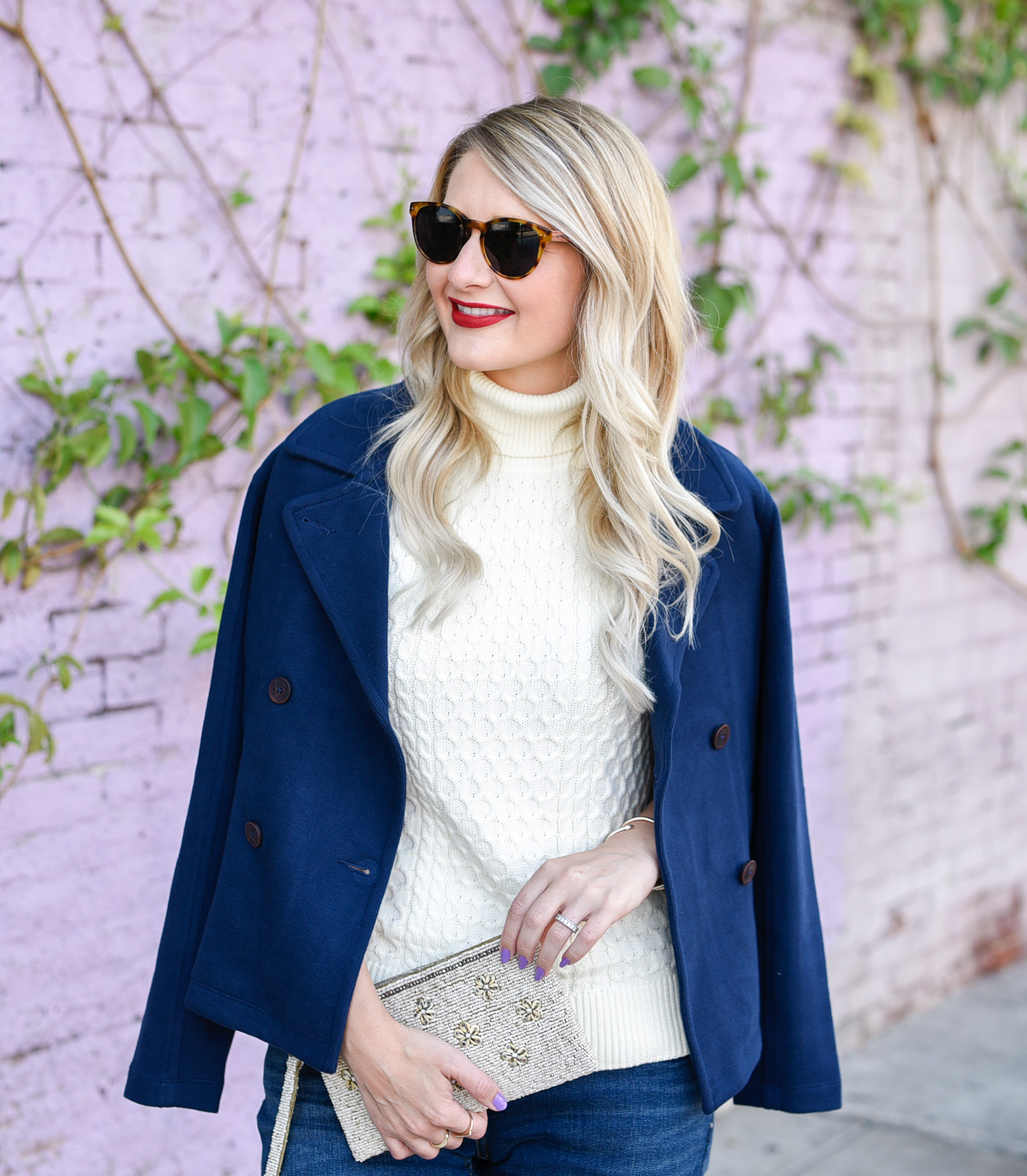 Jenna Colgrove in a sleeveless turtleneck layered under a navy peacoat. 