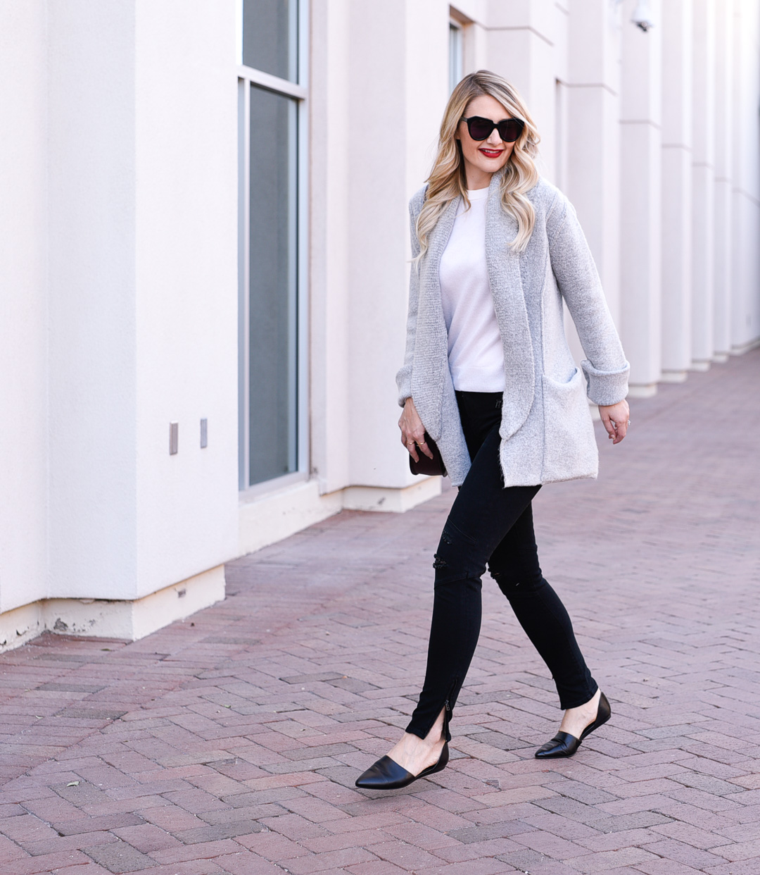Jenna Colgrove wearing a grey cardigan sweater, black skinny jeans, and black leather flats. 