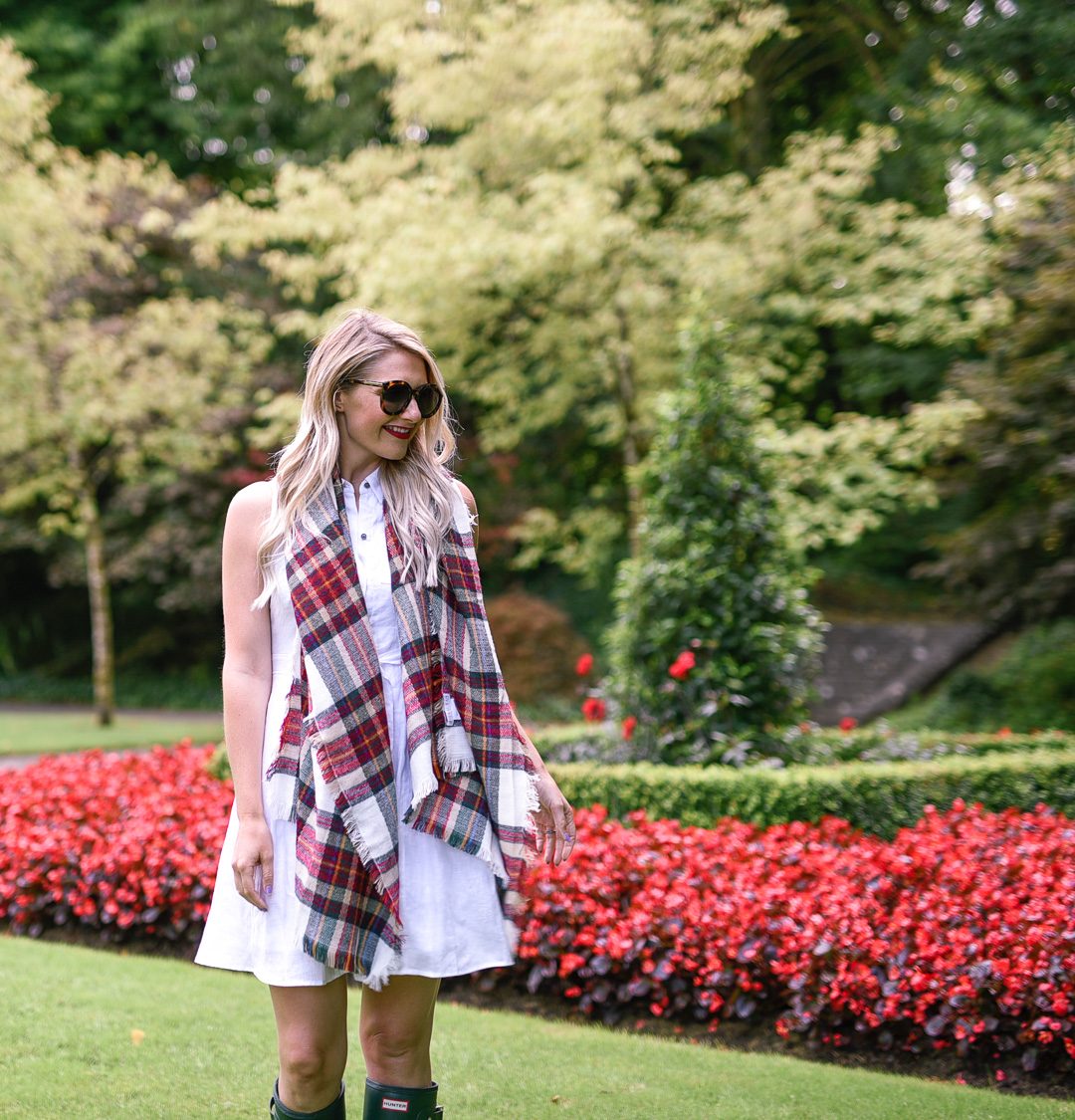 Jenna Colgrove wearing a Nordstrom plaid blanket scarf walking through the gardens at Ashford Castle. 