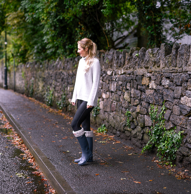 Jenna Colgrove wearing a Dreamers LA grey turtleneck sweater and grey Hunter Boots. 