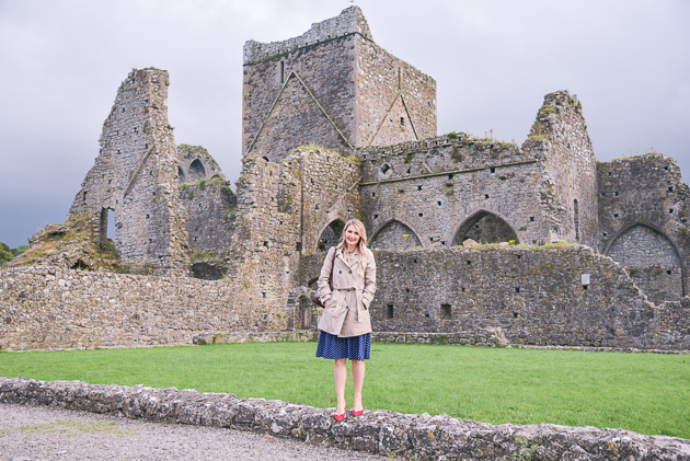 Jenna Colgrove in a beige trench coat at Hore Abbey, Ireland. 