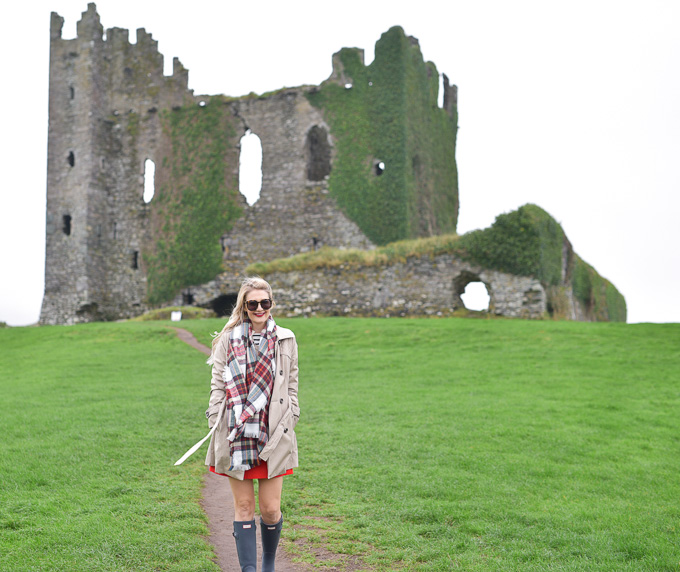 Jenna Colgrove in Hunter rain boots and a brown jacket at Ballycarbery Castle ruins in Ireland.