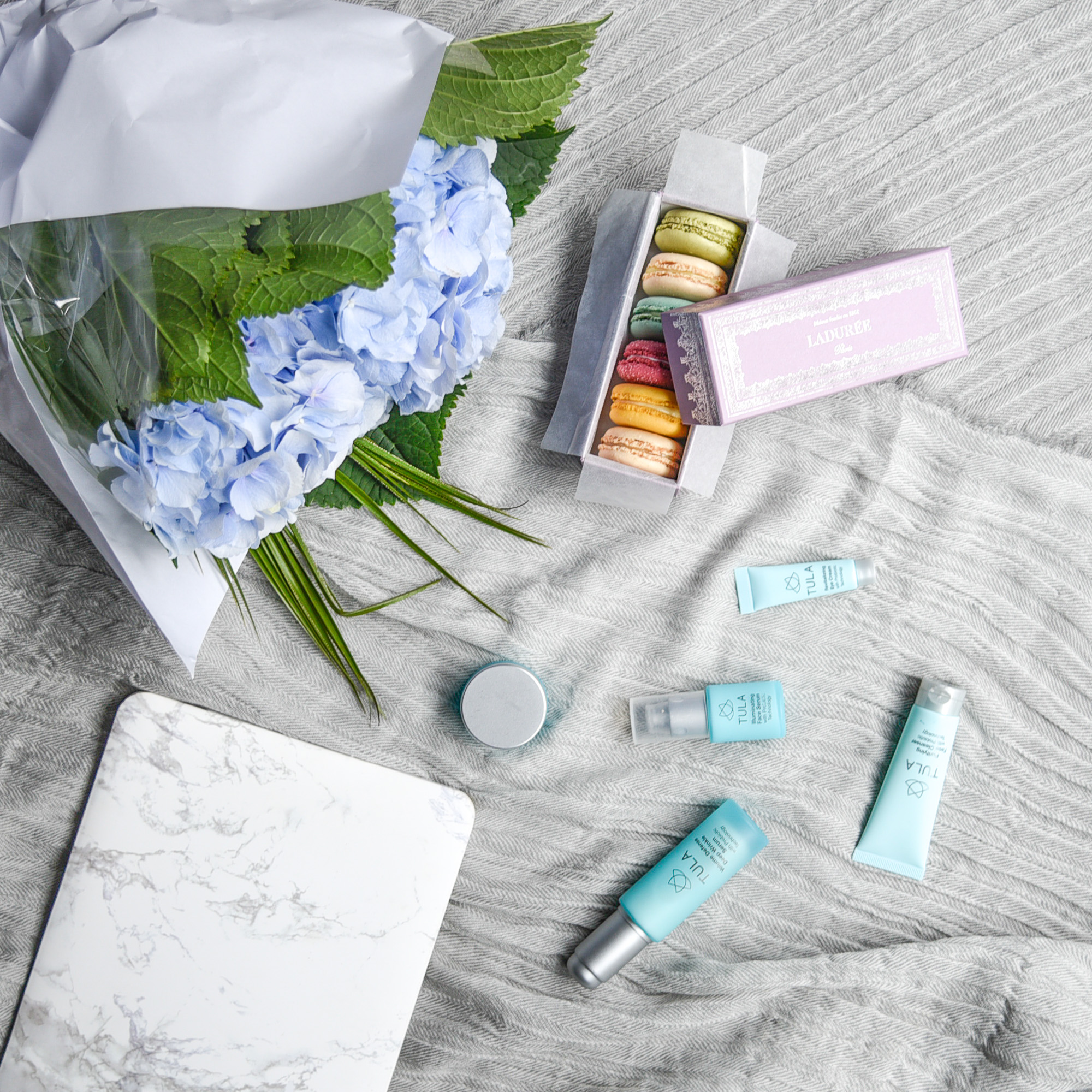 Travel sized TULA beauty products and hydrangeas.