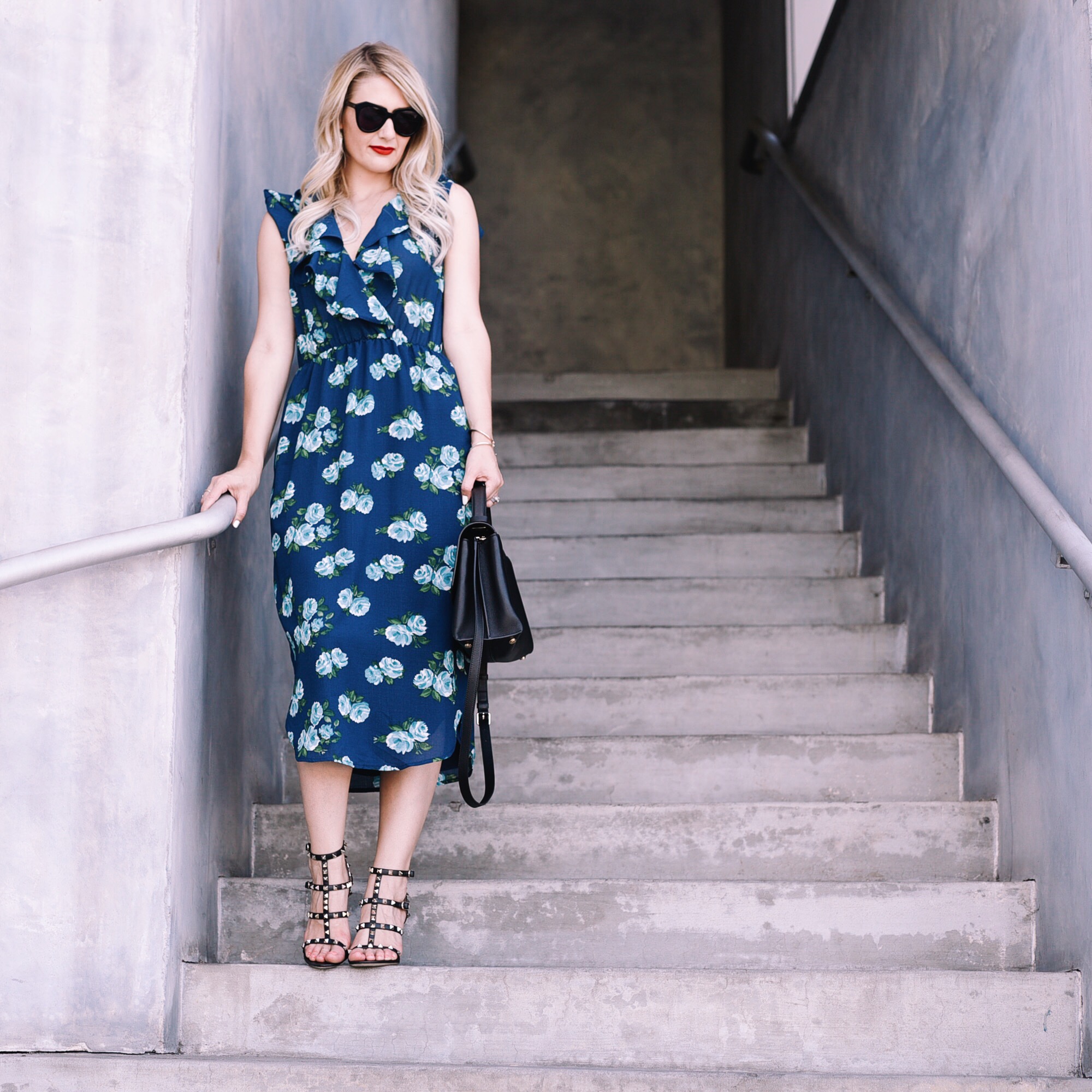 Jenna Colgrove wearing a blue WAYF floral midi dress and Valentino Rockstude Ankle Strap Heels. 