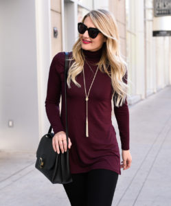 Jenna Colgrove wearing a wine colored turtleneck sweater and a Kendra Scott Phara tassel necklace.