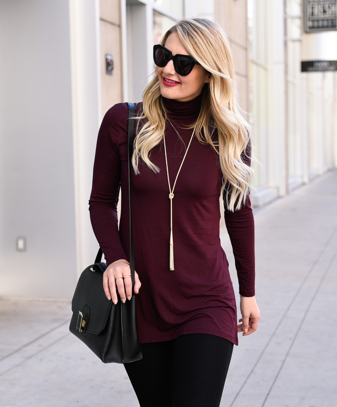 Jenna Colgrove wearing a wine colored turtleneck sweater and a Kendra Scott Phara tassel necklace. 