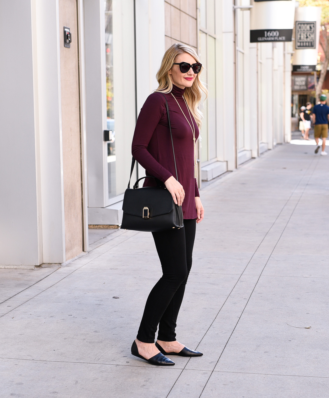 Jenna Colgrove wearing an oxblood turtleneck and black leggings with flats. 