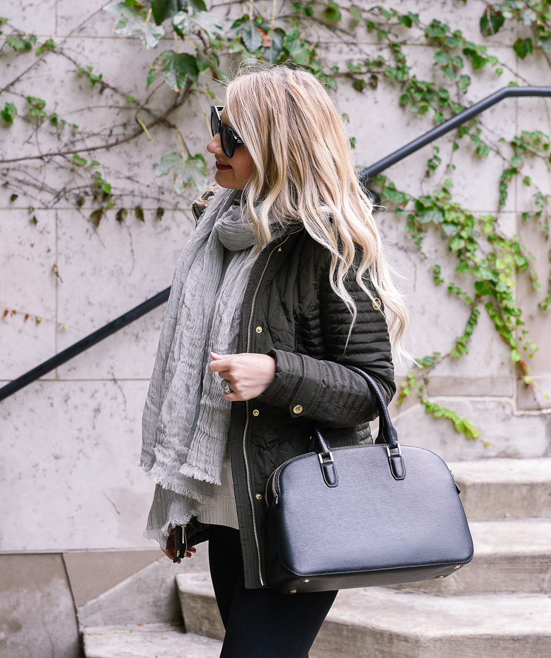 Jenna Colgrove wearing a black Henri Bendel crossbody, a hunter green coat, and in wand curls. 