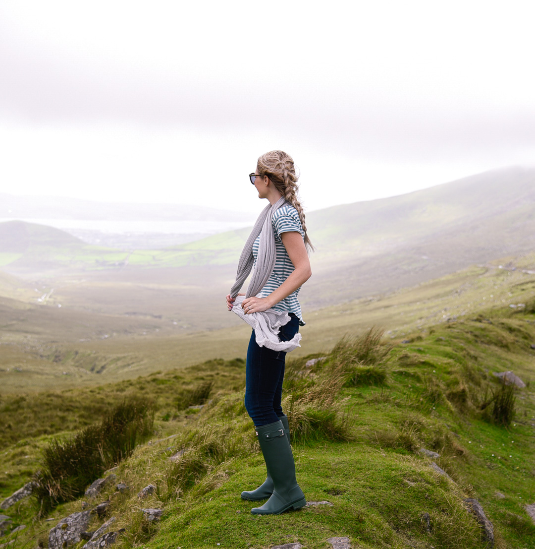 Jenna Colgrove looking over a valley on the Dingle Peninsula in Paige Skinny jeans, Hunter boots, and a Caslon scarf. 