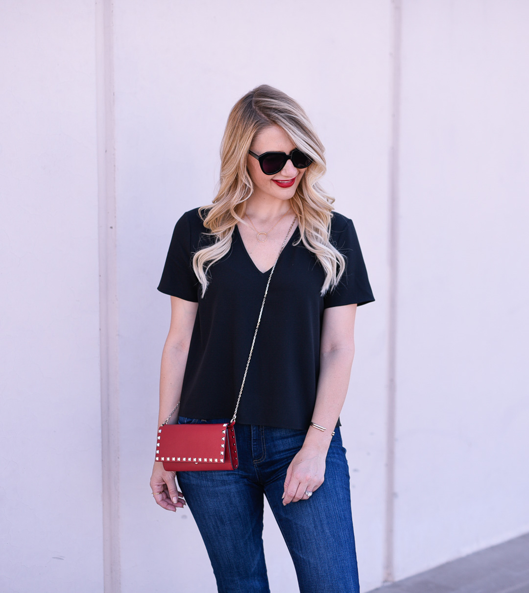 Jenna Colgrove wearing a red Valentino rockstud purse and a black v neck shirt. 