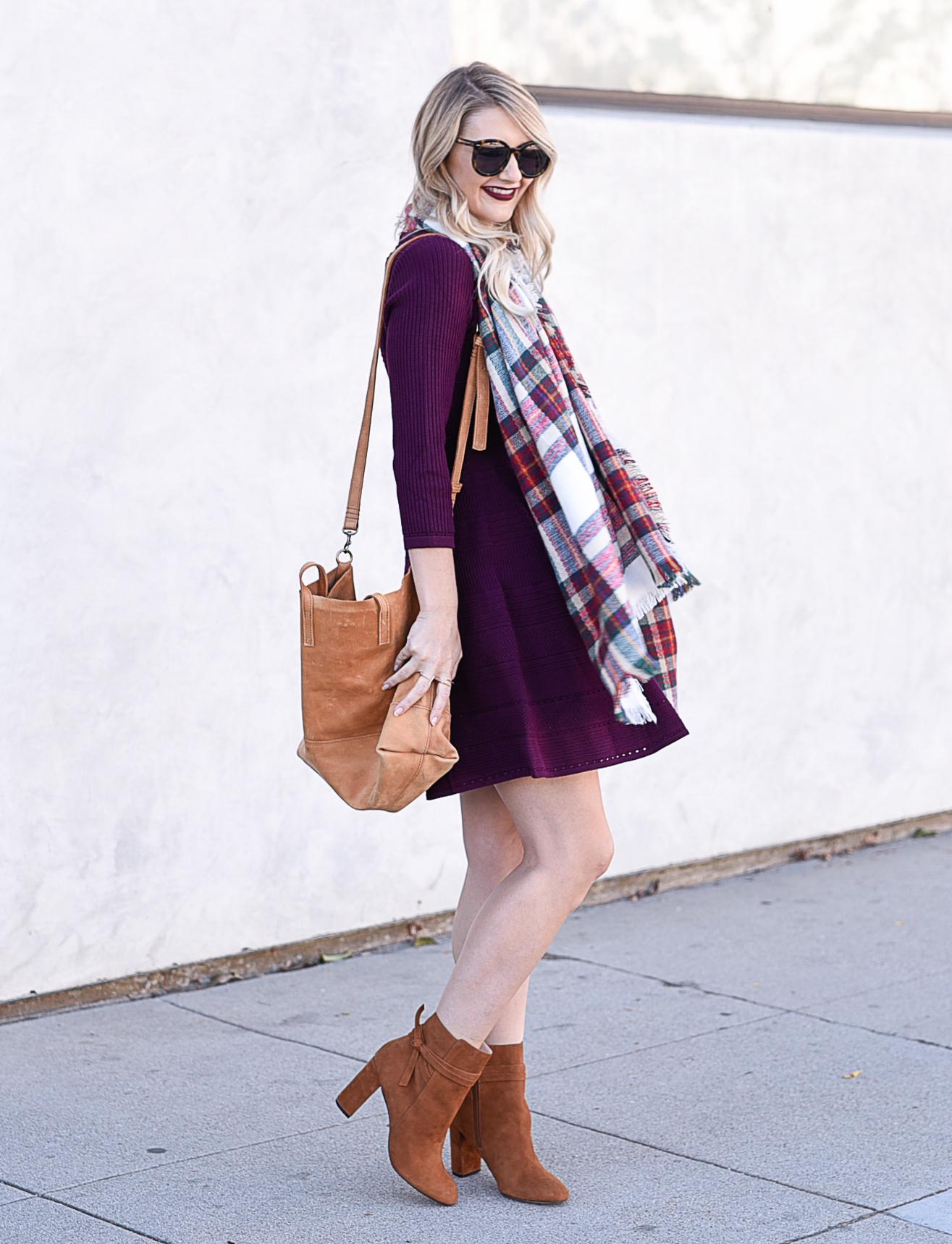 Jenna Colgrove wearing an Eliza J sweater dress in burgundy and a cognac tote bag. 