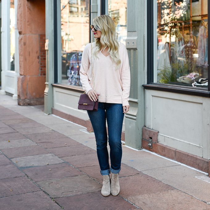 Visions of Vogue wearing a light pink knit sweater, skinny jeans, and taupe booties with a cutout. 