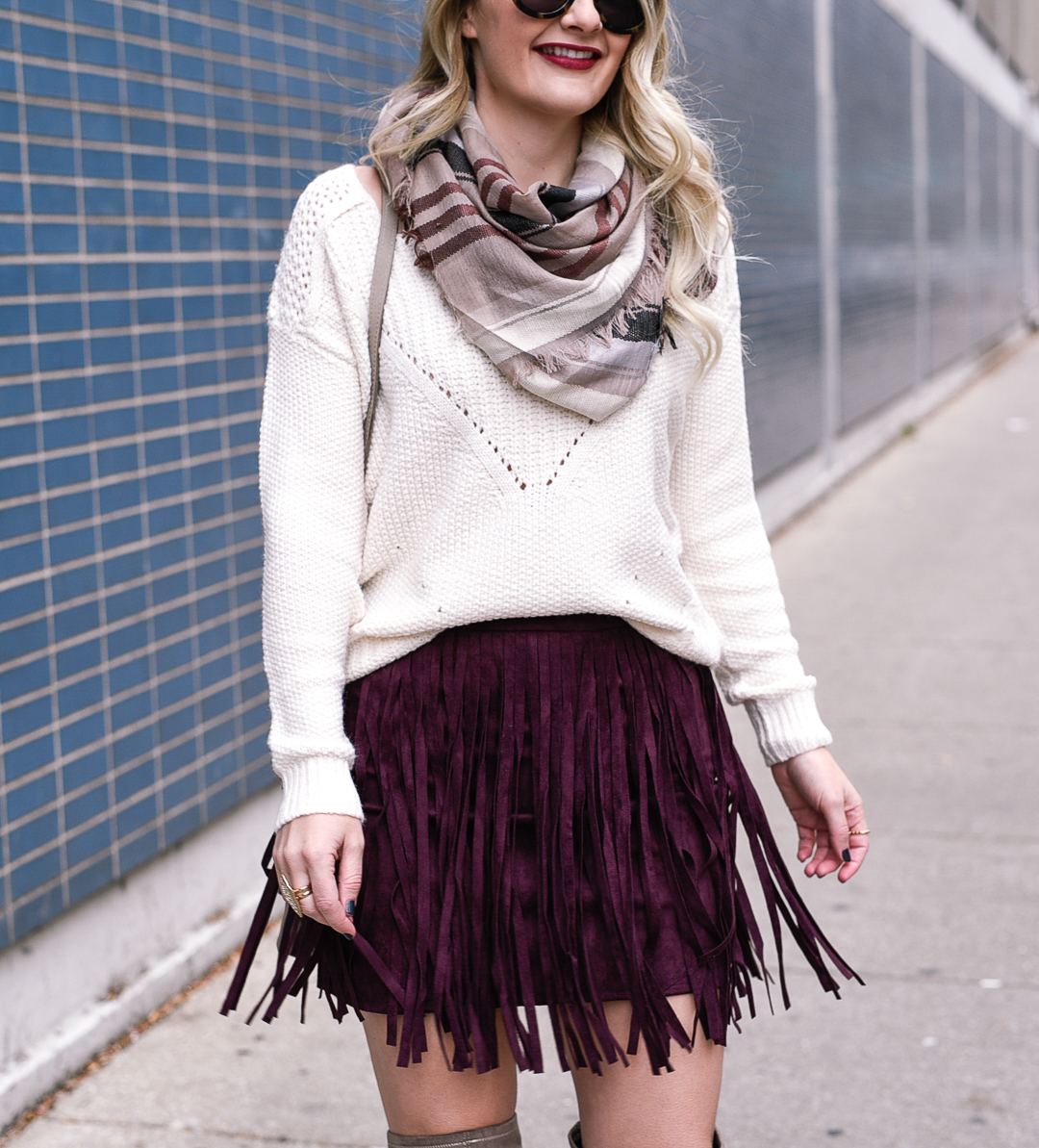 Jenna Colgrove wearing a cozy plaid scarf, oversized knit, and suede mini skirt. 