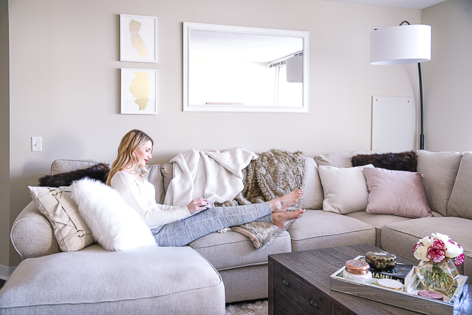 Jenna Colgrove reading a book at home with Minted wall art and a decorative white mirror. 