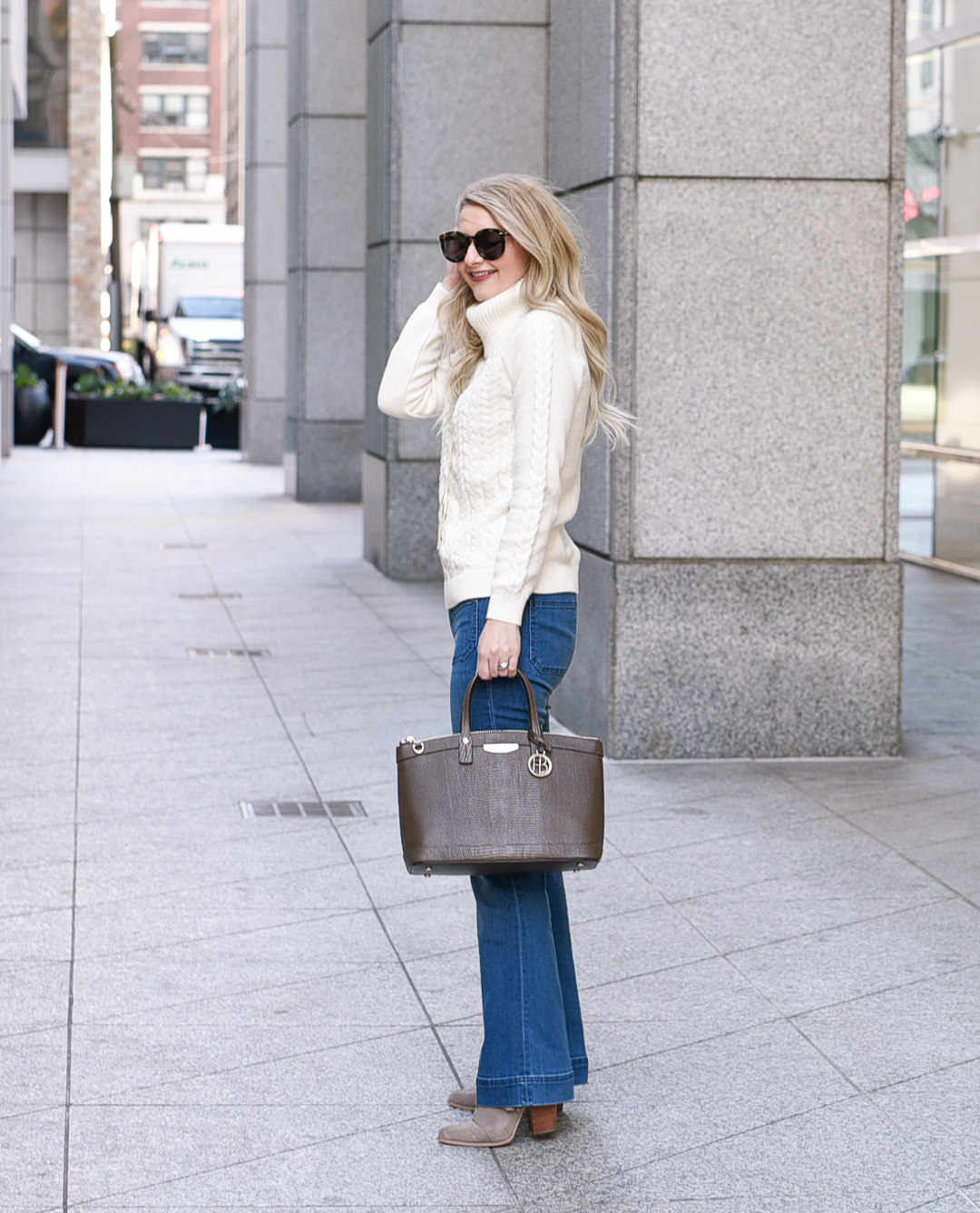 Jenna Colgrove in Tommy Bahama flared denim jeans and a white turtleneck sweater. 