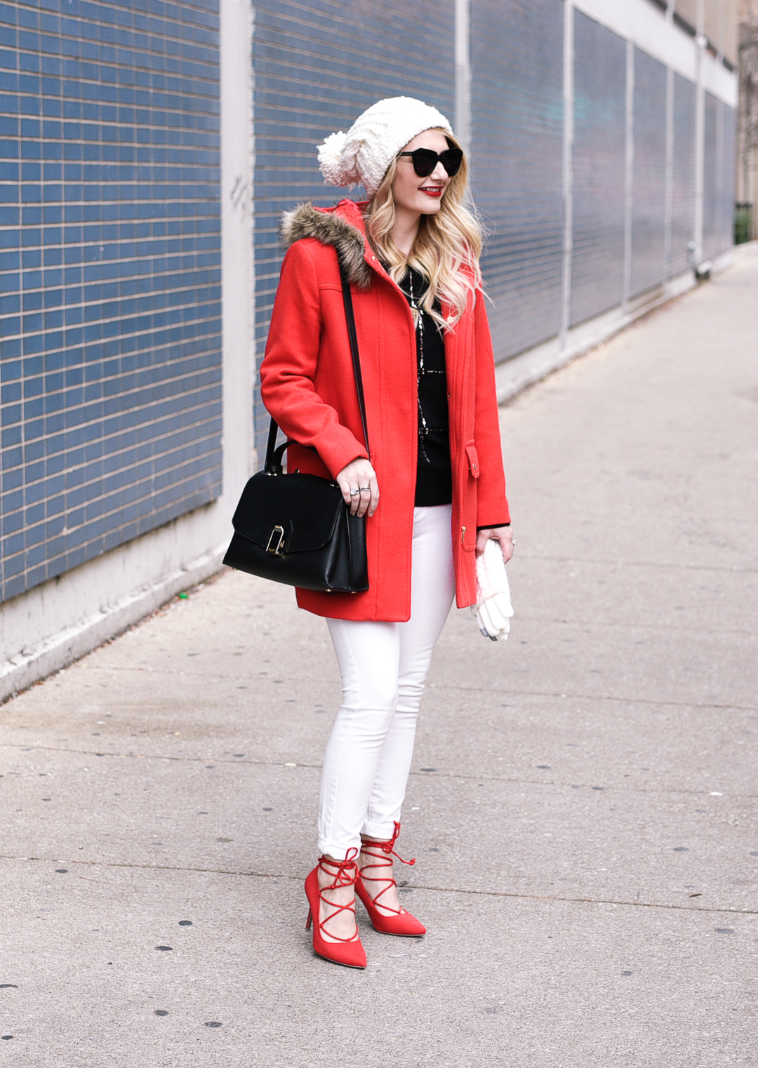 Jenna Colgrove wearing the J.Crew Vail Parka, an embellished sweater, white skinny jeans, and red suede heels. 