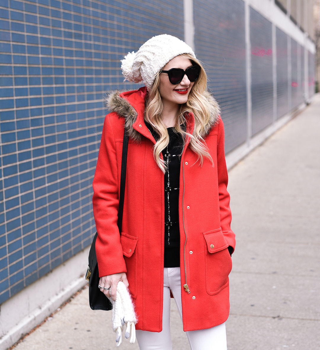 Jenna Colgrove wearing an embellished sweater, red fur parka, and white beanie.