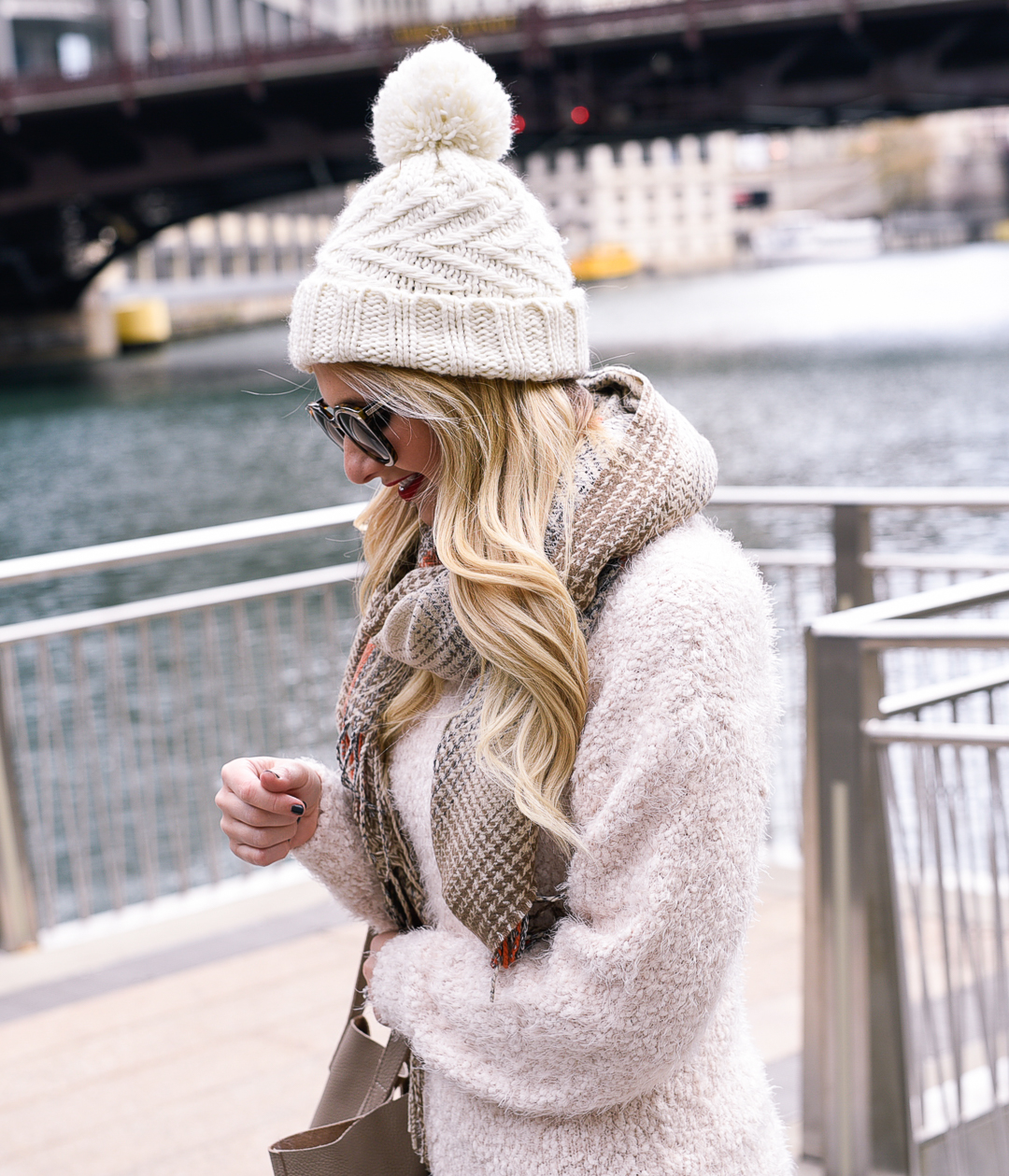 Jenna Colgrove wearing a white cable knit beanie and a plaid scarf. 