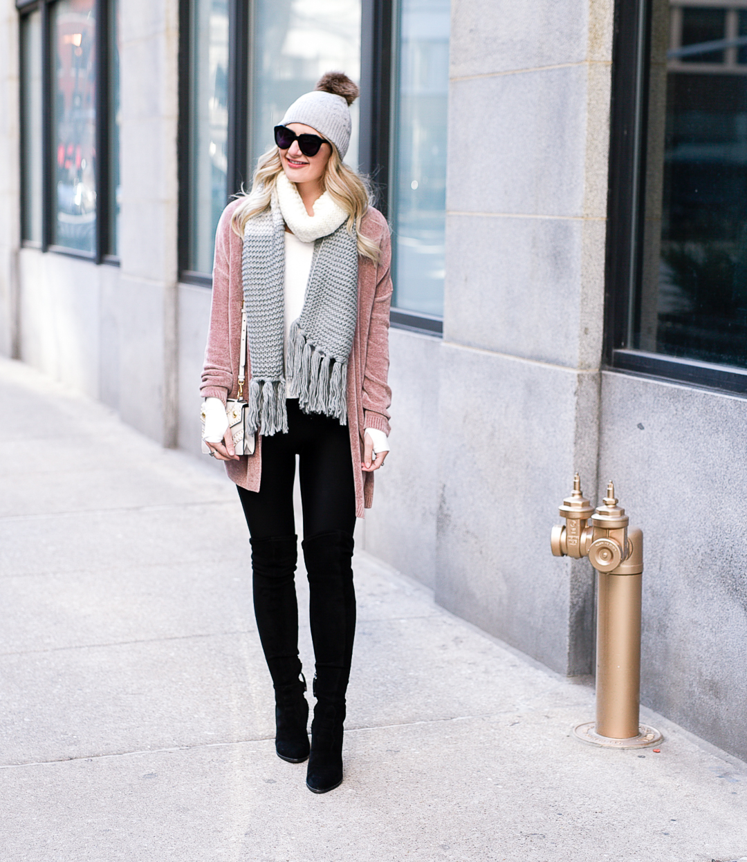 Blush pink cardigan, grey fringe scarf, and a pom beanie.