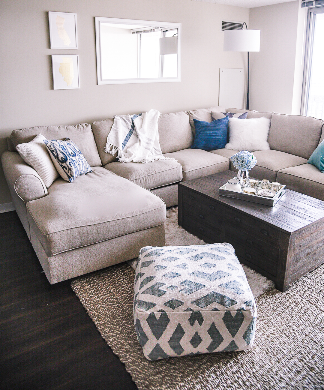 a blue ikat pouf with a white neutral living room sectional 