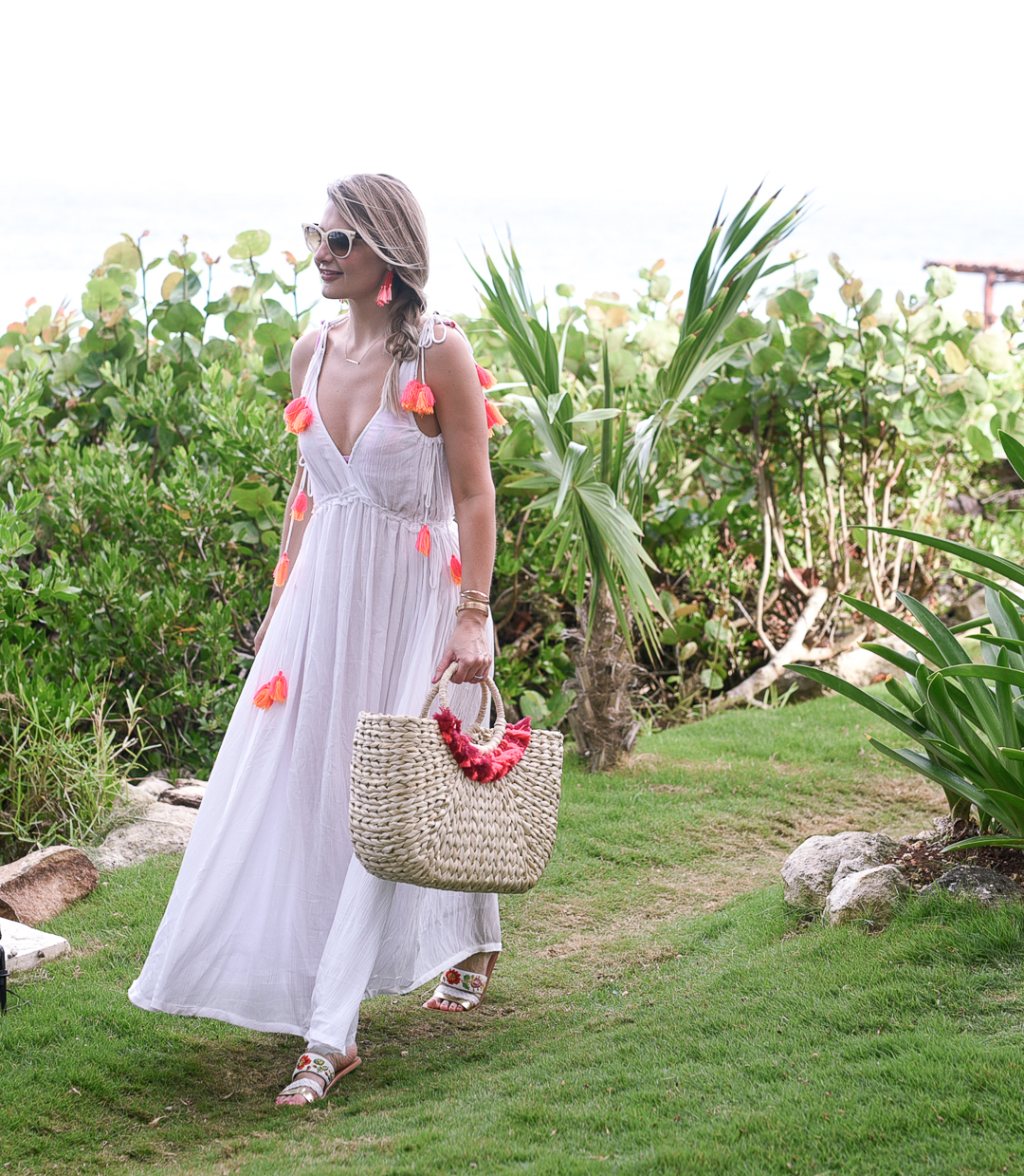 A white maxi beach cover up with orange and red tassels