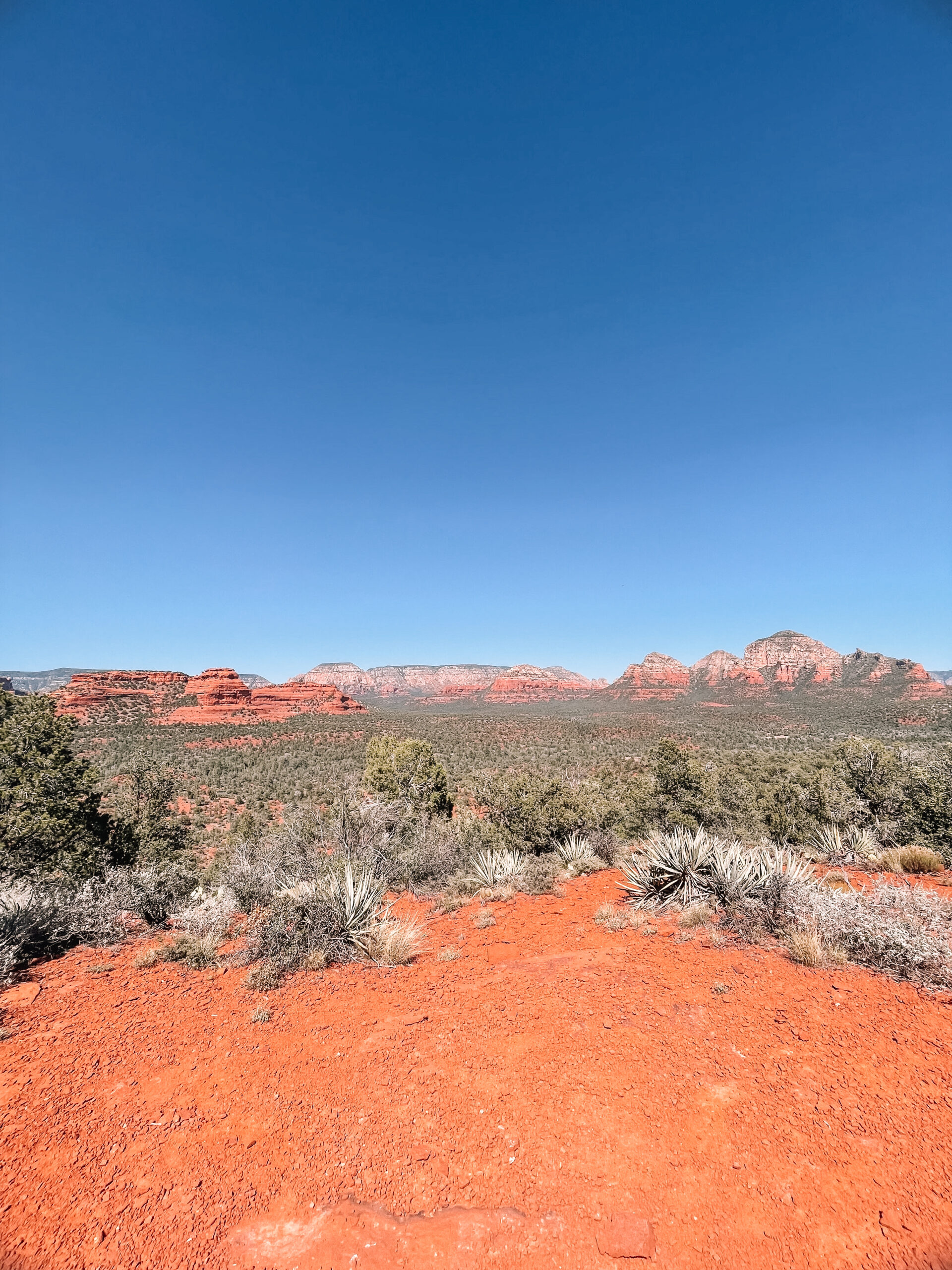 Scenic red rock hiking trail in Sedona, Arizona with blue sky, desert landscape, and travelers exploring the path